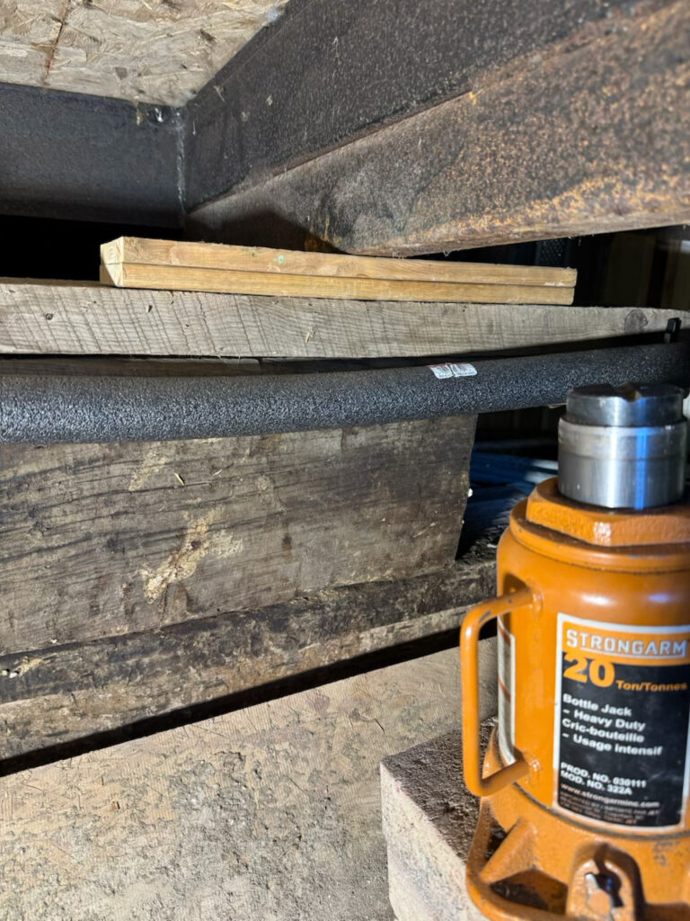 Using a powerful jack to lift beams in the crawl space to level floors